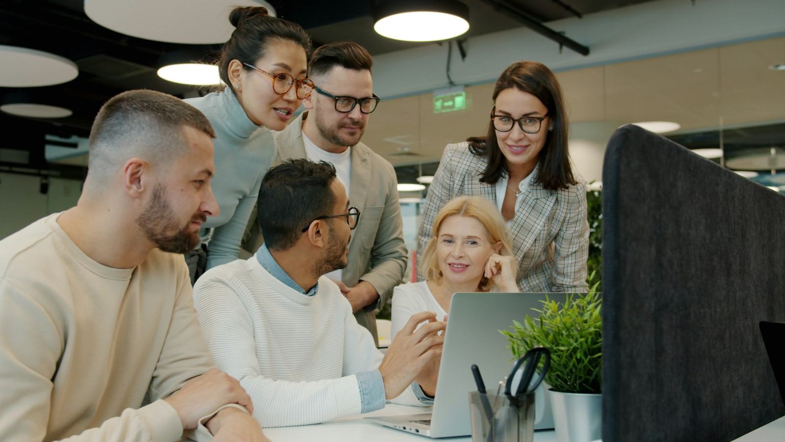 A diverse team working together around a laptop